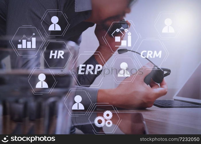 Architecture of ERP (Enterprise Resource Planning) system with connections between business intelligence (BI), production, CRM modules and HR diagram.Man using VOIP headset with digital tablet computer.