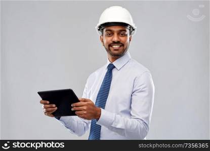 architecture, technology, construction business and building - smiling indian architect or businessman in helmet with tablet computer over grey background. architect or businessman in helmet with tablet pc