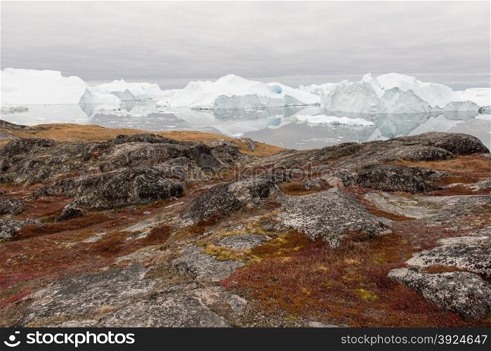 Arctic landscape in Greenland around Disko Island with icebergs, ocean, mountains and cloudscape