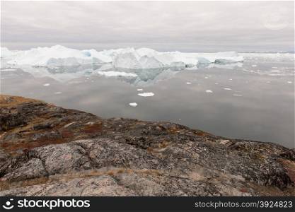 Arctic landscape in Greenland around Disko Island with icebergs, ocean, mountains and cloudscape