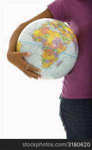 Arm and hips of African American woman holding globe.