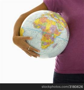 Arm and hips of African American woman holding globe.