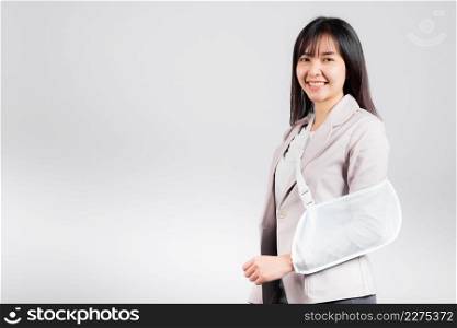 Arm broken. Business woman confident smiling broken arm after accident and wear arm splint for treatment, excited happy Asian female sling support hand studio isolated on white background, copy space