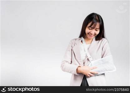 Arm broken. Business woman confident smiling broken arm after accident and wear arm splint for treatment, excited happy Asian female sling support hand studio isolated on white background, copy space