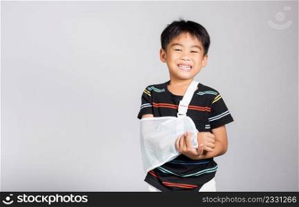 Arm broken. Little cute kid boy 5-6 years old hand bone broken from accident with arm splint in studio shot isolated on white background, Asian children preschool injured after accident, health concept