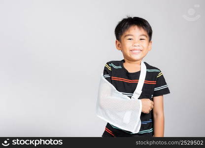 Arm broken. Little cute kid boy 5-6 years old hand bone broken from accident with arm splint in studio shot isolated on white background, Asian children preschool injured after accident, health concept