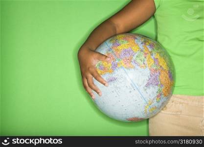 Arm of African American girl holding globe at hip.
