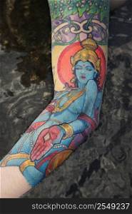 Arm of tattooed Caucasian woman by tidal pool in Maui, Hawaii, USA.
