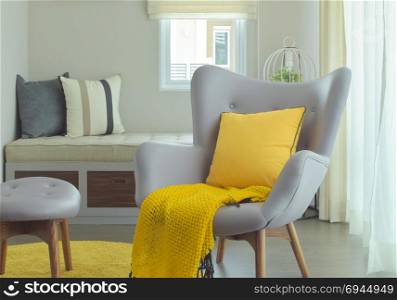 Armchair and yellow pillow and scarf in modern style living corner