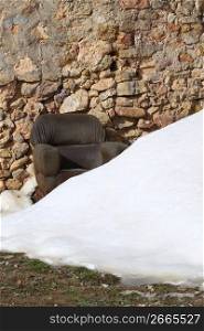 armchair on snowed stone masonry wall relax metaphor