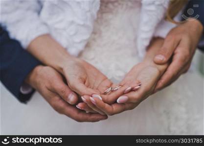 Arms of hands of the newlyweds.. The husband embraces the brides hands with wedding rings 756.. The husband embraces the brides hands with wedding rings 756.