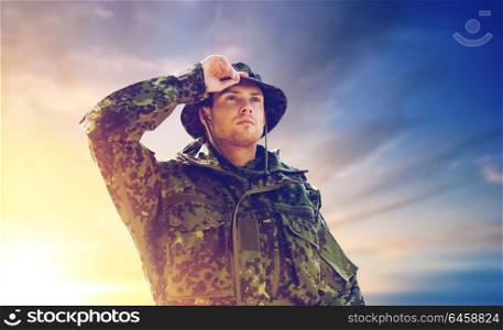 army, national service and people concept - young soldier or ranger wearing military uniform and jungle hat over sky background. young soldier in military uniform over sky