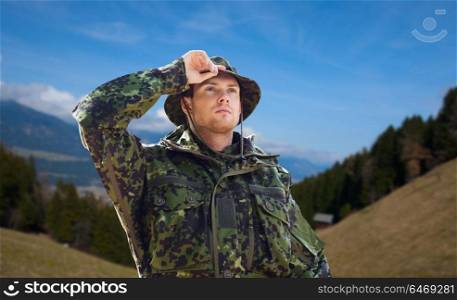 army, national service and people concept - young soldier or ranger wearing military uniform and jungle hat over mountains background. young soldier in military uniform outdoors