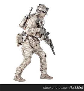 Army soldier, equipped infantryman, airsoft player in camouflage battle uniform, helmet and tactical radio headset jumping, running with assault rifle in hand studio shoot isolated on white background. Running soldier with rifle isolated studio shoot