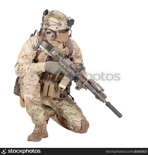 Army special forces infantry in battle uniform, radio headset on helmet, armed service rifle, standing on knee, waiting in ambush, patrolling area, observing territory studio shoot isolated on white. Soldier with rifle standing on knee studio shoot