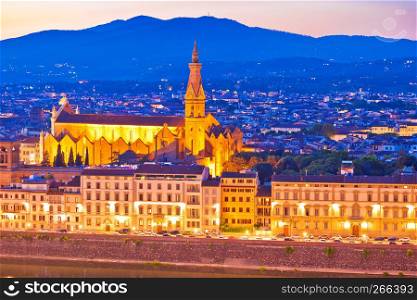 Arno river waterfront and illuminated church in Florence evening view, Tuscany region of Italy