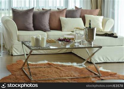 Aroma candles and wine glasses on the table with beige sofa and deep brown pillows in modern living room