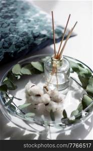 aromatherapy and decoration concept - close up of aroma reed diffuser, cotton flowers and eucalyptus in low glass vase at home. aroma reed diffuser, cotton flowers and eucalyptus