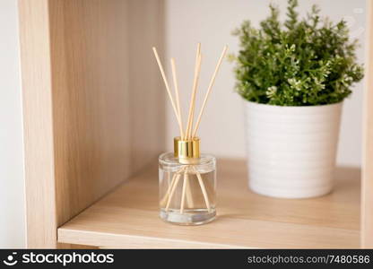 aromatherapy and home perfume concept - aroma reed diffuser and pot flower on wooden shelf. aroma reed diffuser and pot flower on wooden shelf