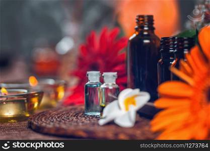 Aromatherapy composition with transparent aromatherapy bottles filled with blue and green essential oils, colorful red and orange flowers and candles. Aromatherapy relax concept.