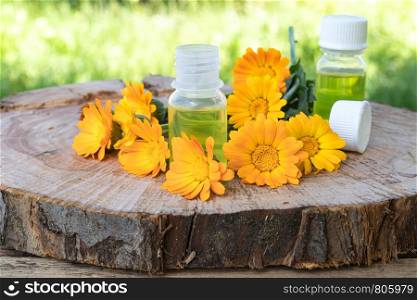 Aromatherapy essential oil with calendula flowers on a wooden background in nature. Extract of tincture of calendula. Medicinal plants.. Aromatherapy essential oil with calendula flowers on a wooden background in nature. Extract of tincture of calendula.