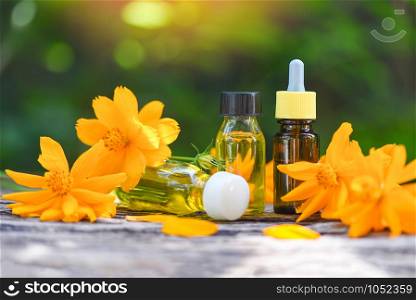 Aromatherapy herbal oil bottles aroma with flower yellow on nature green background / Essential oils natural for face and body beauty remedies on wooden table and organic minimalist lifestyle