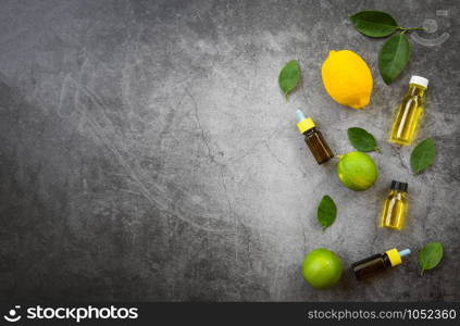 Aromatherapy herbal oil bottles aroma with lemon and lime leaves herbal formulations top view / Essential oils natural on black background and green leaf organic flat lay