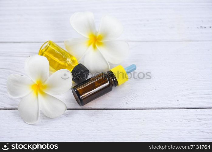Aromatherapy herbal oil bottles aroma with white flower Frangipani Plumeriaon top view / Essential oils natural on wooden table and organic minimalist