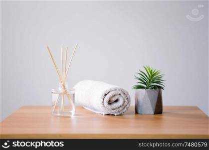 aromatherapy, spa and home perfume concept - aroma reed diffuser, bath towel and succulent on wooden table. aroma reed diffuser, bath towel and succulent