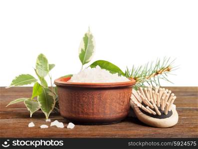 Aromatic bath salt in a clay cup and comb on a wooden background