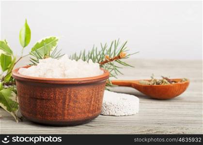 Aromatic bath salt in a clay cup and pumice stone on a wooden background.
