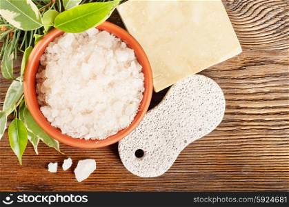 Aromatic bath salt in a clay cup and pumice stone on a wooden background