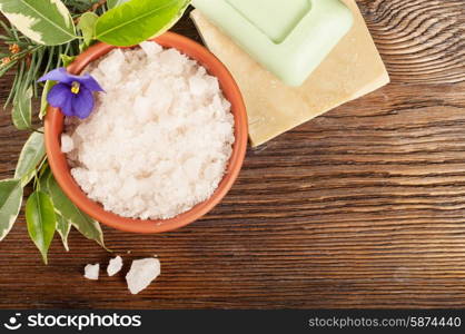 Aromatic bath salt in a clay cup and soap on a wooden background