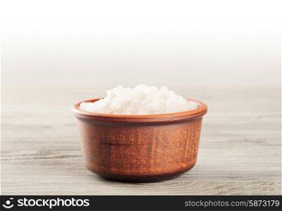 Aromatic bath salt in a clay cup on a wooden surface