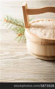 Aromatic bath salt in wooden bucket and pine branch