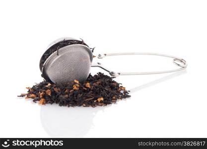 Aromatic black dry tea with petals and a tea strainer on white reflective background.