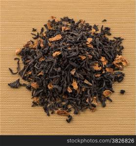 Aromatic black dry tea with petals, on yellow textured background.