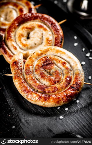 Aromatic grilled sausages with a ruddy crust. On a black background. High quality photo. Aromatic grilled sausages with a ruddy crust.