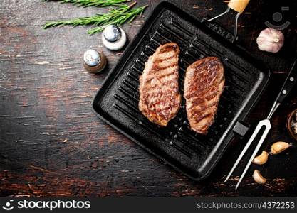 Aromatic grilled steak in a frying pan. Against a dark background. High quality photo. Aromatic grilled steak in a frying pan.