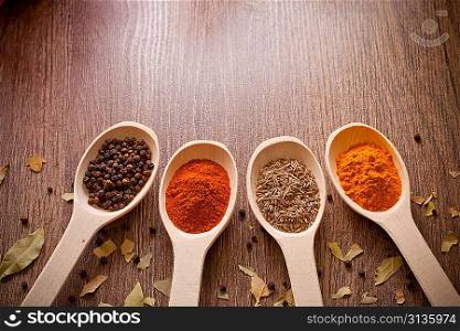 aromatic powder spices on spoons in wooden background