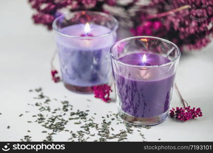 Aromatic purple scented candles with lavender decoration on a white table.. Aromatic Purple Scented Candles with Lavender Decoration