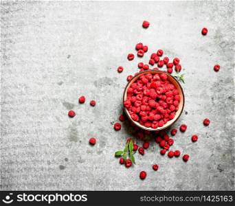 Aromatic raspberries in a bowl. On a stone background.. Aromatic raspberries in a bowl.
