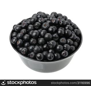 Aronia berries in a black cup on a white background, isolated