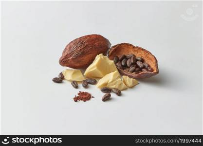 Arranged half of cocoa pod filled with beans and composed with cocoa butter and cocoa powder as products of Theobroma manufacturing. Cocoa beans in pods and butter