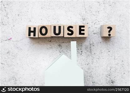 arranged house text blocks with question sign paper house model against concrete backdrop