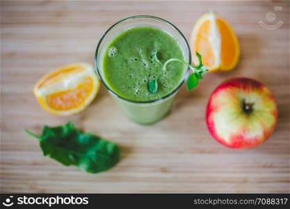 Arrangement of a fresh green healthy smoothie and fruits on a wooden background