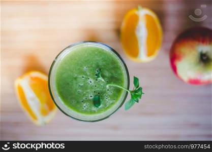 Arrangement of a fresh green healthy smoothie and fruits on a wooden background