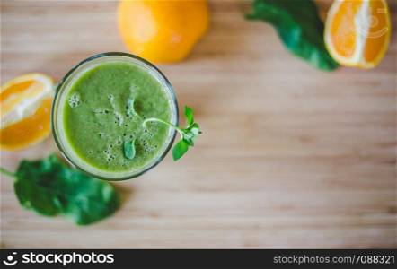 Arrangement of a fresh green healthy smoothie and fruits on a wooden background. Text space.