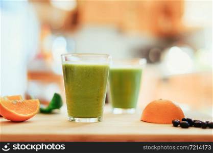 Arrangement of a fresh green healthy smoothies and fruits in the kitchen.