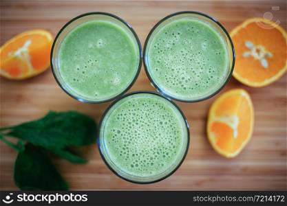 Arrangement of a fresh green healthy smoothies and fruits on a wooden background.